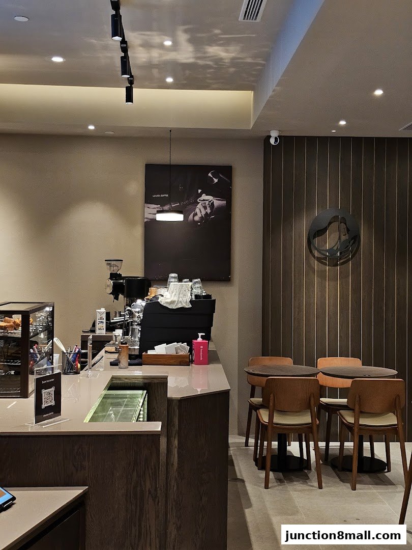 Interior of a modern coffee shop with a counter, seating, and artwork.