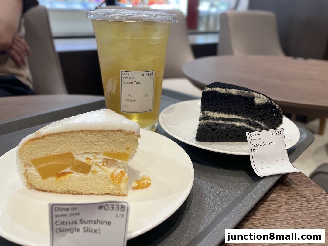 Two slices of cake and a green tea drink on a tray in a cafe.