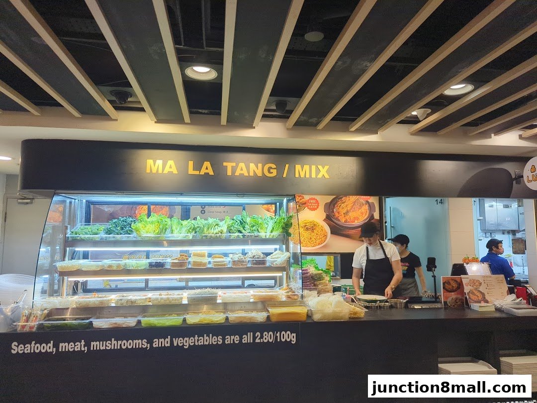 A food stall with fresh ingredients displayed and staff preparing meals.