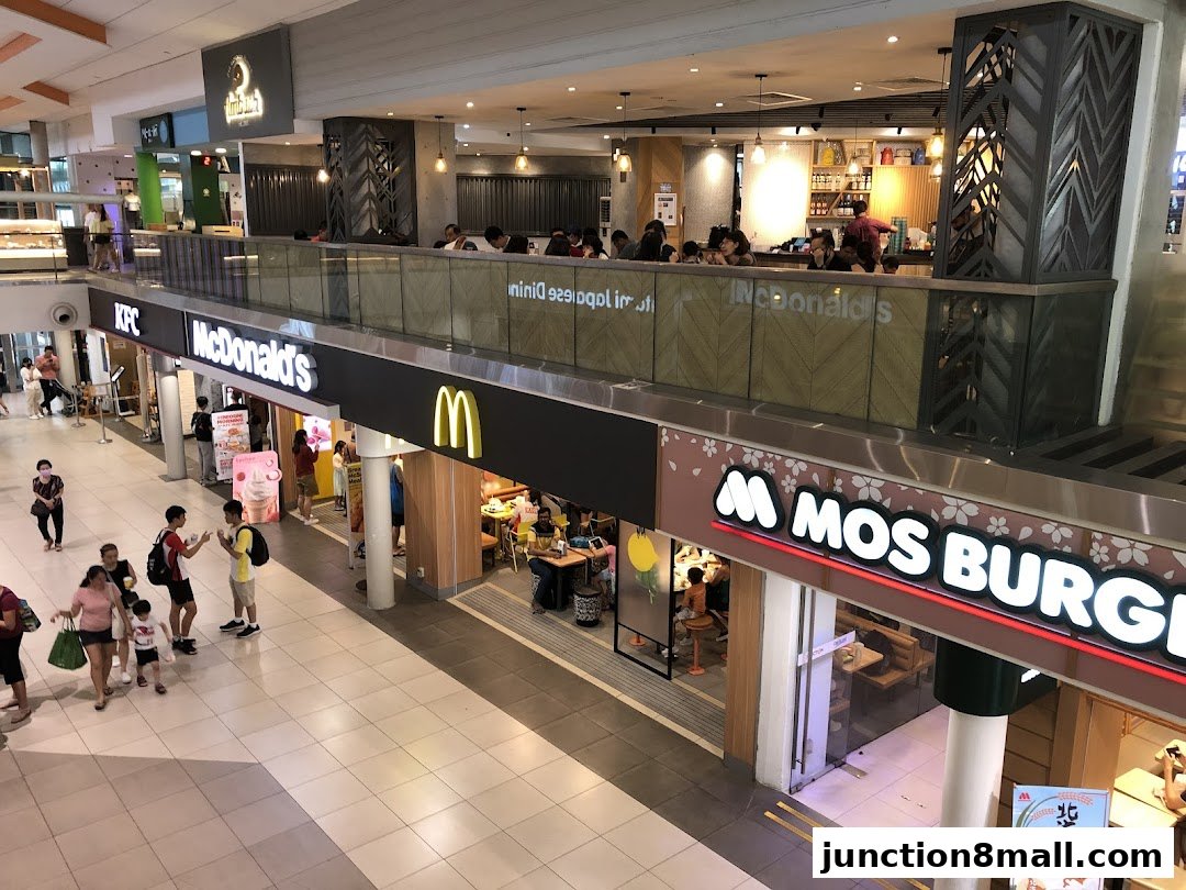 View of McDonald's and Mos Burger outlets in a shopping mall with customers.