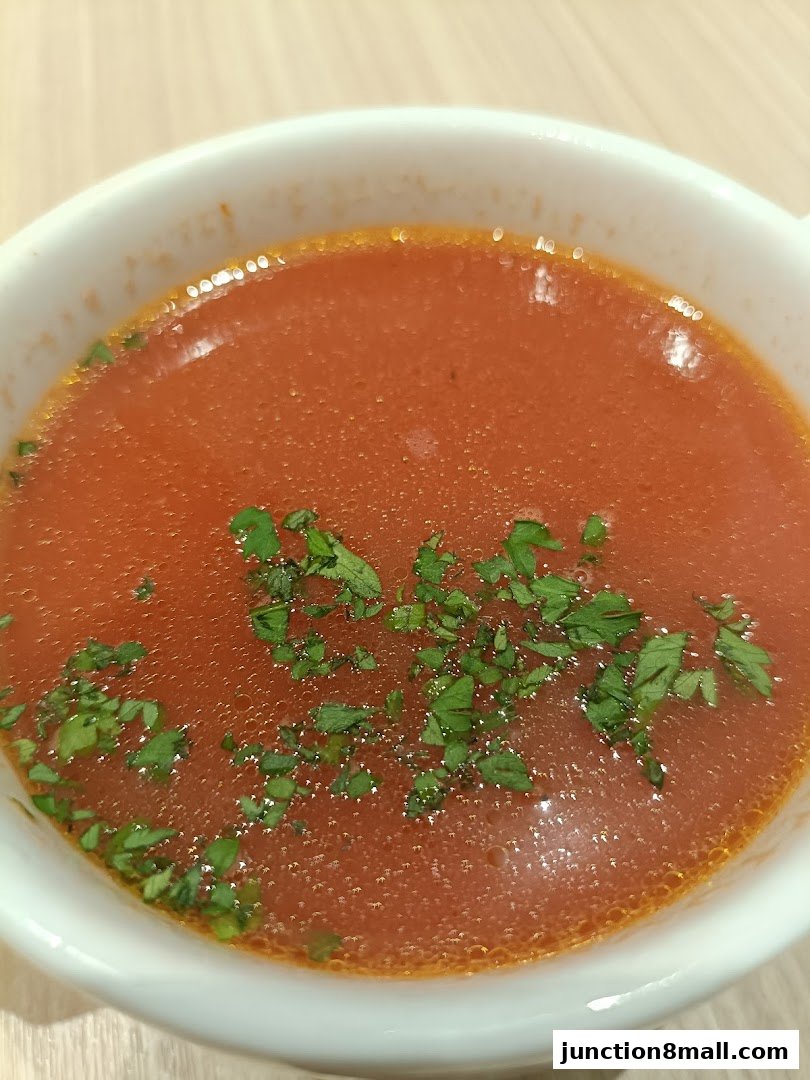 A close-up shot of a steaming bowl of tomato soup garnished with fresh parsley.