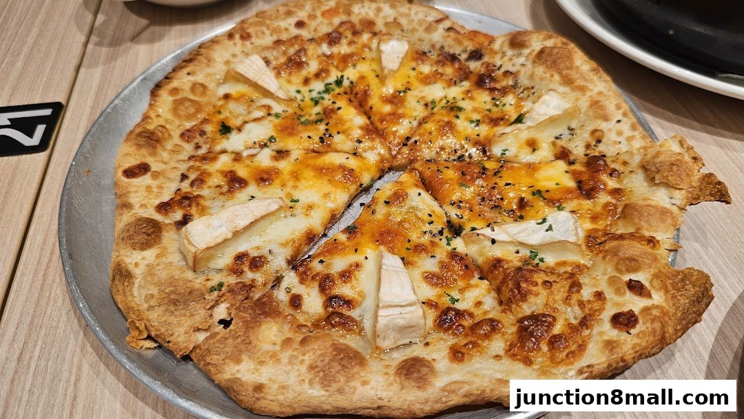 A delicious-looking pizza with melted cheese and herbs on a metal plate.