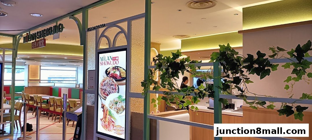 The exterior of Milan Shokudo Junction 8, featuring its signage, a digital menu, and interior seating.