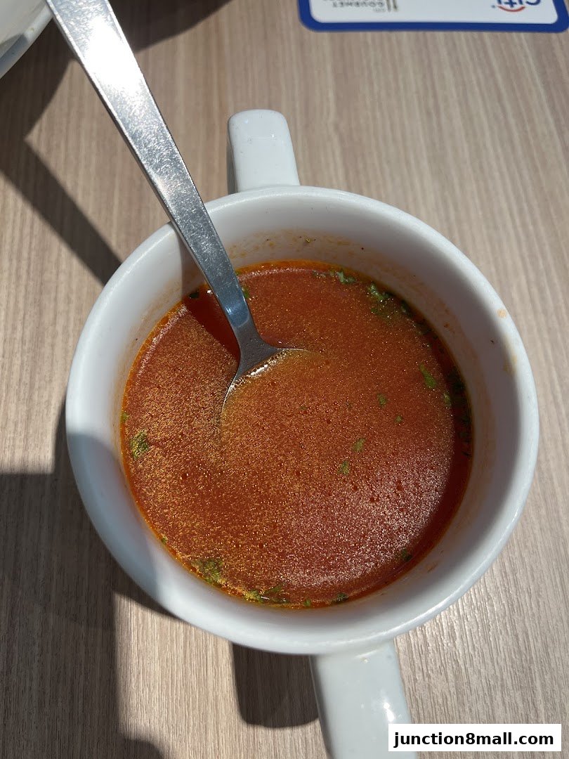 A close-up shot of a steaming bowl of tomato soup with a spoon.