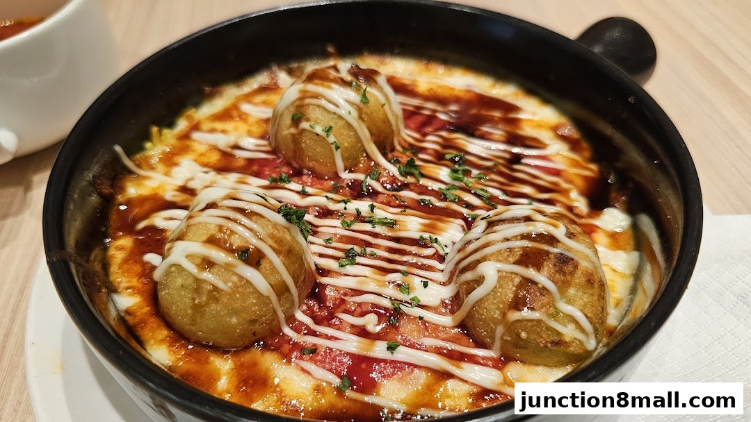 A close-up of a delicious dish with takoyaki balls, cheese, and sauce.
