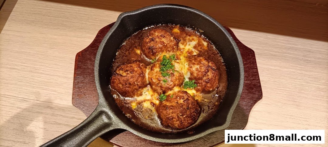 A sizzling skillet of five cheesy meatballs topped with fresh parsley.