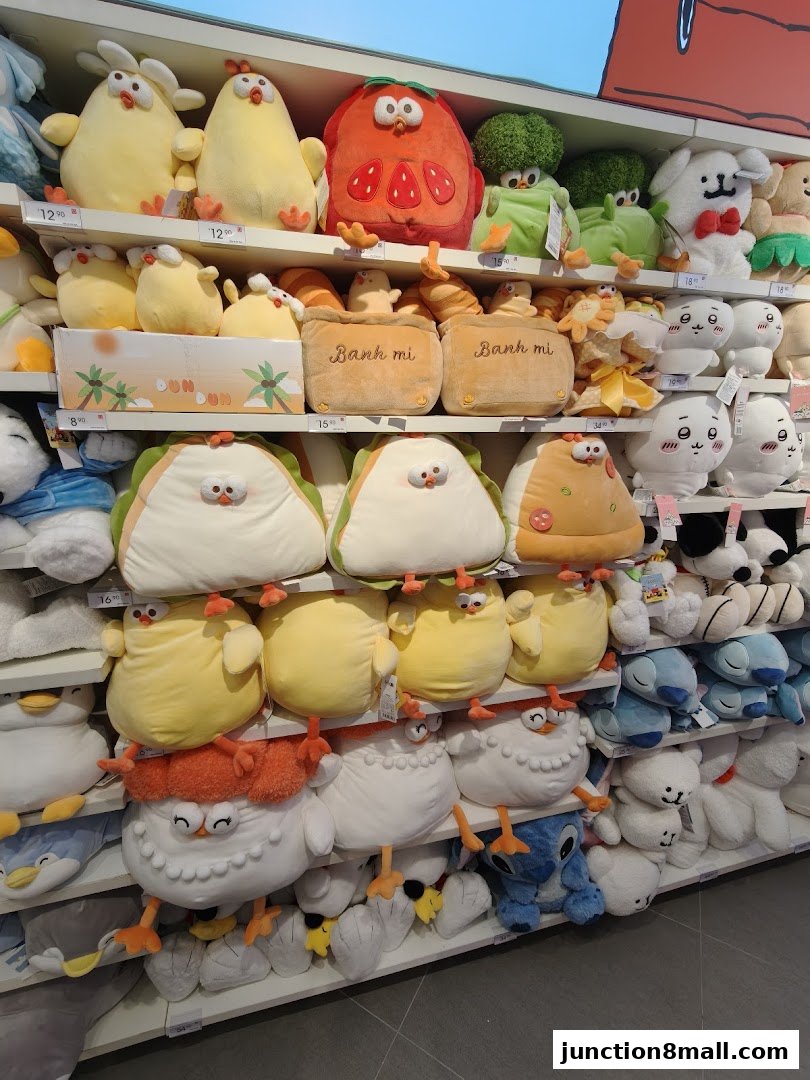 A display of cute, plush toys including chickens, strawberries, broccoli, and other characters on shelves.