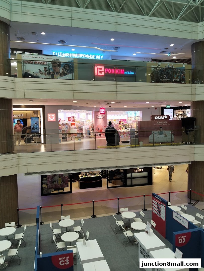 A multi-level shopping mall interior with various shops and event booths.