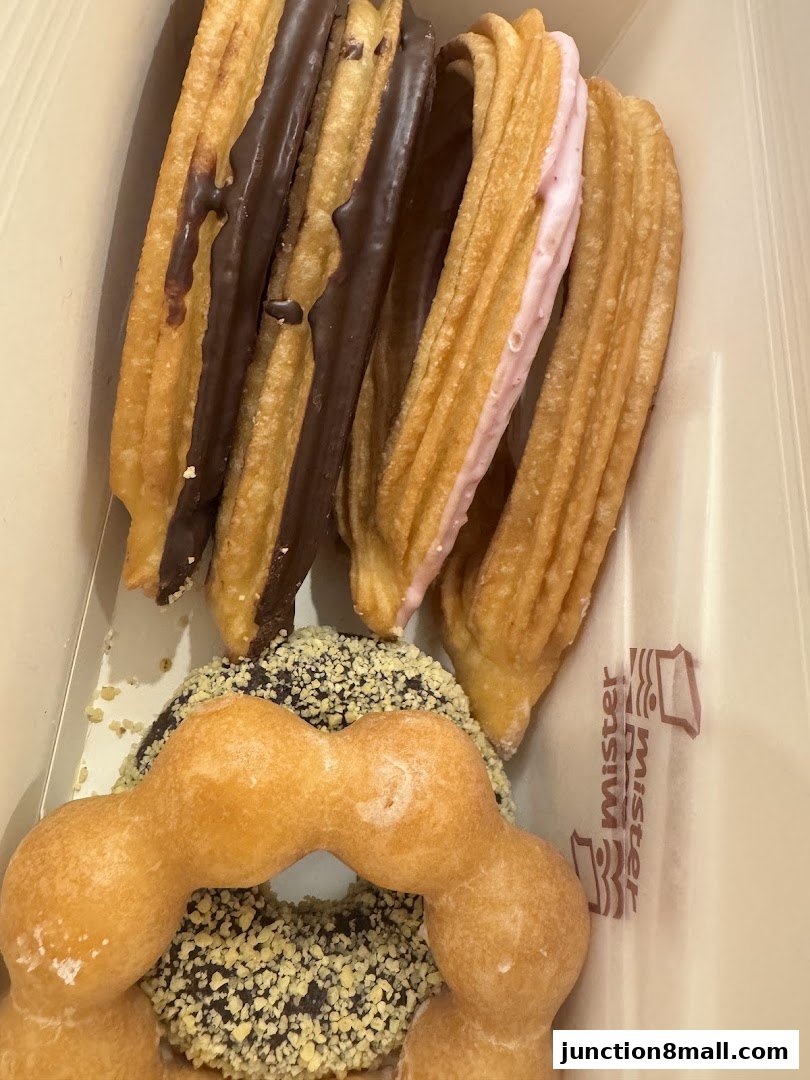 A box of assorted donuts and churros, some with chocolate and strawberry filling.
