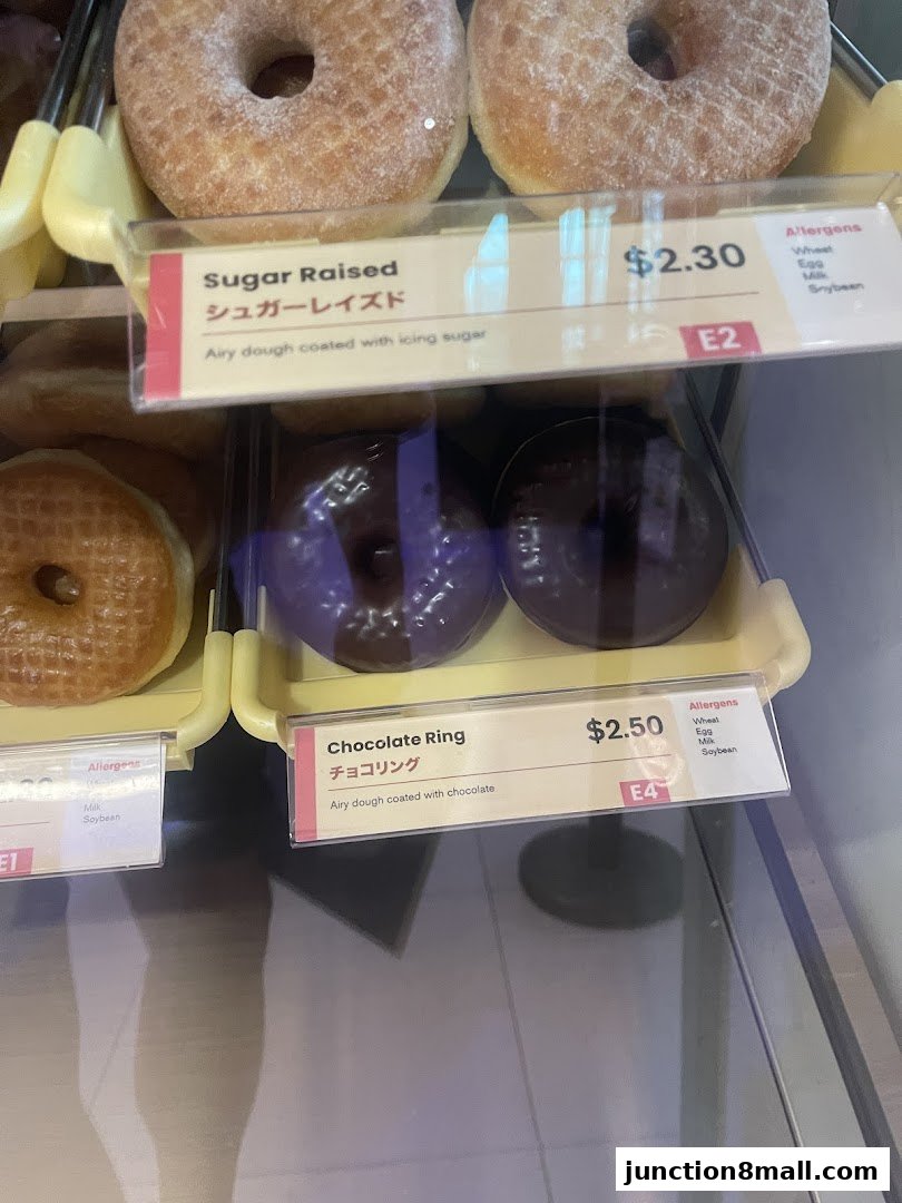 A display of freshly made donuts with their names and prices.
