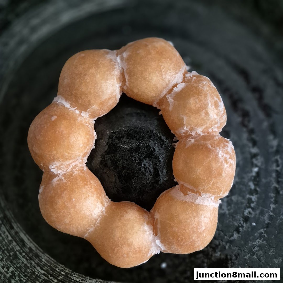 A close-up shot of a mochi donut with a light glaze on a dark textured surface.