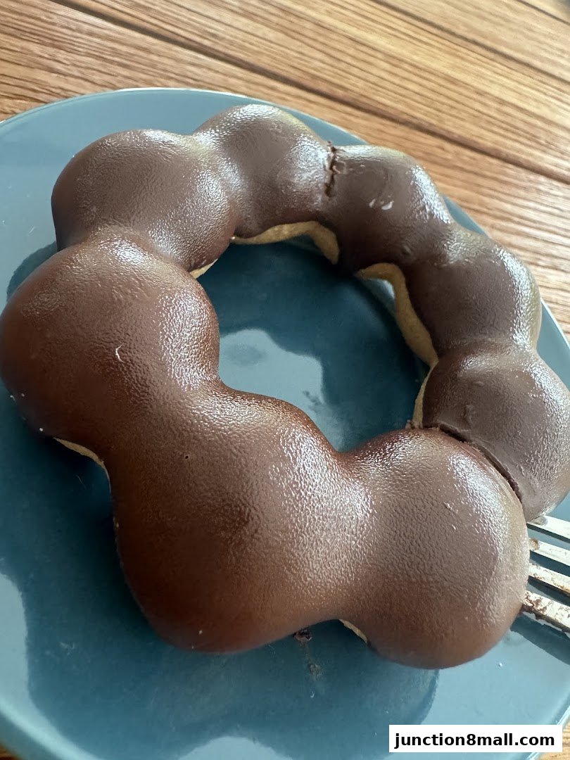 A close-up of a chocolate-glazed mochi donut on a blue plate.