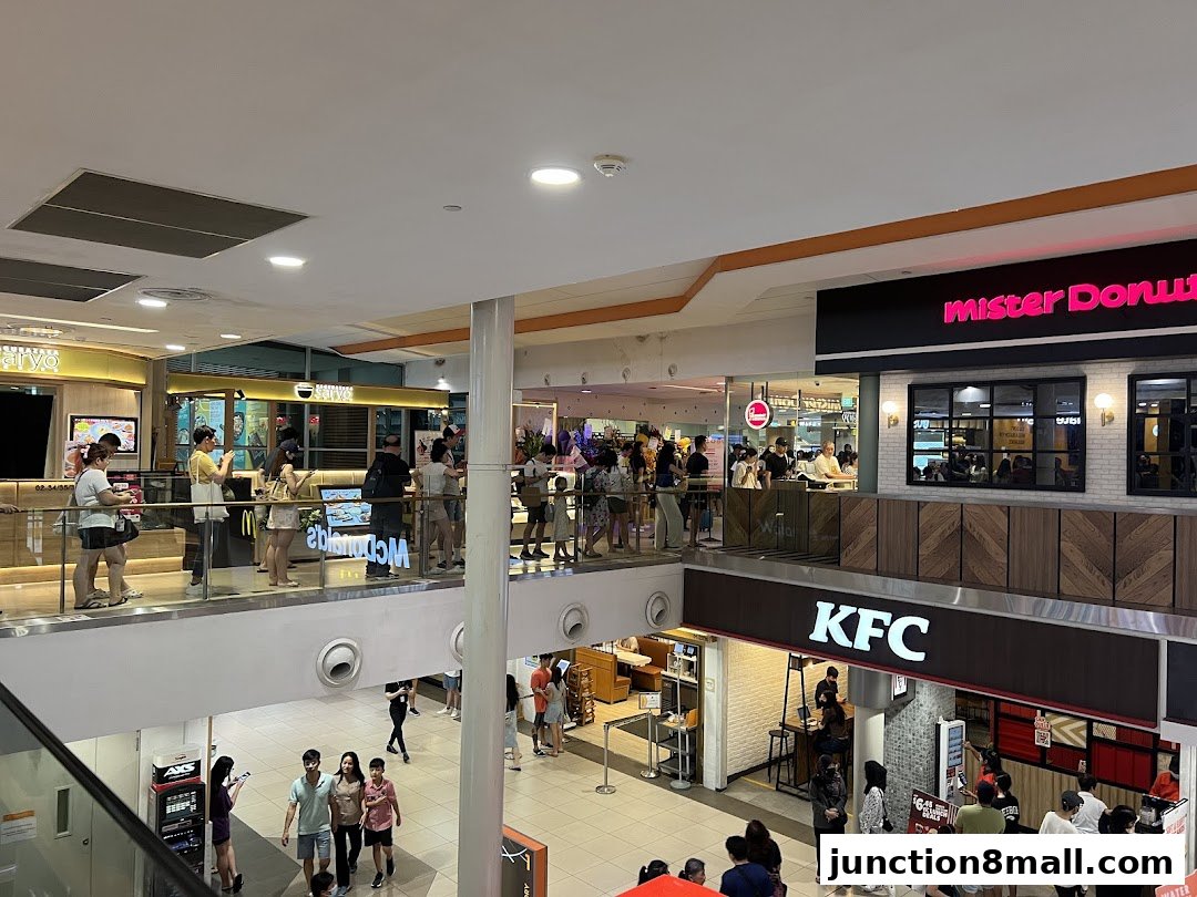 A busy shopping mall interior with several food outlets and shoppers.