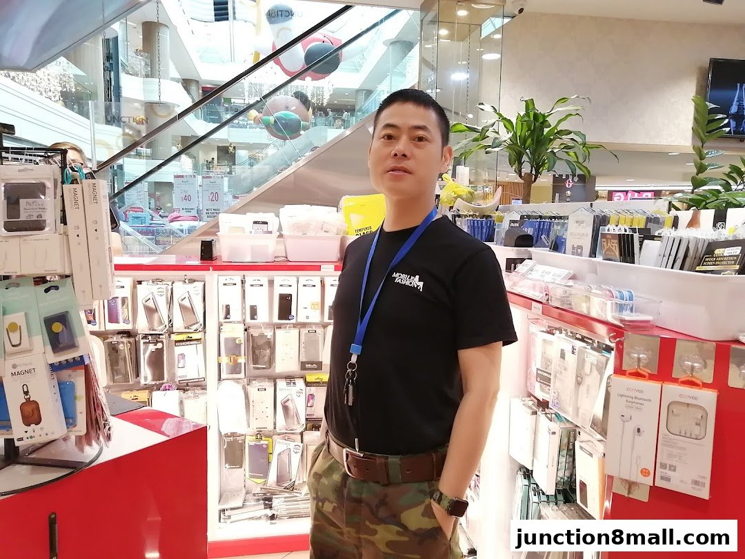 A man stands in front of a display of mobile phone accessories at Mobile Fashion.