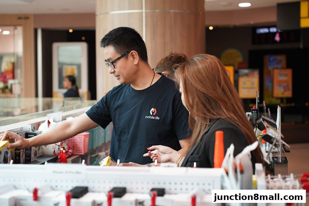 A shop assistant helps a customer at a mobile phone accessories display.