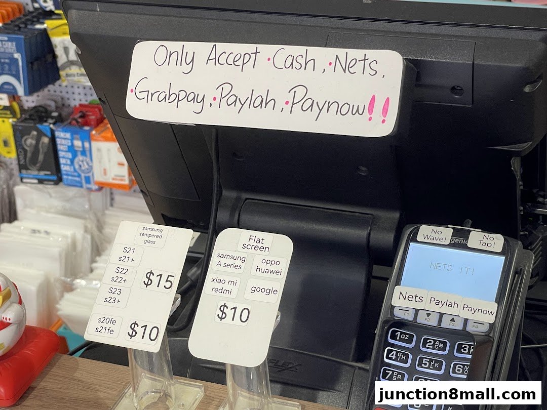 A close-up of a payment terminal and price tags for phone accessories at a retail store.