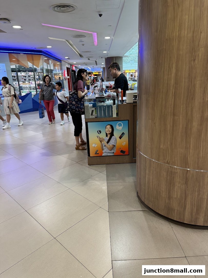 A customer interacts with a staff member at a mobile phone repair counter in a mall.