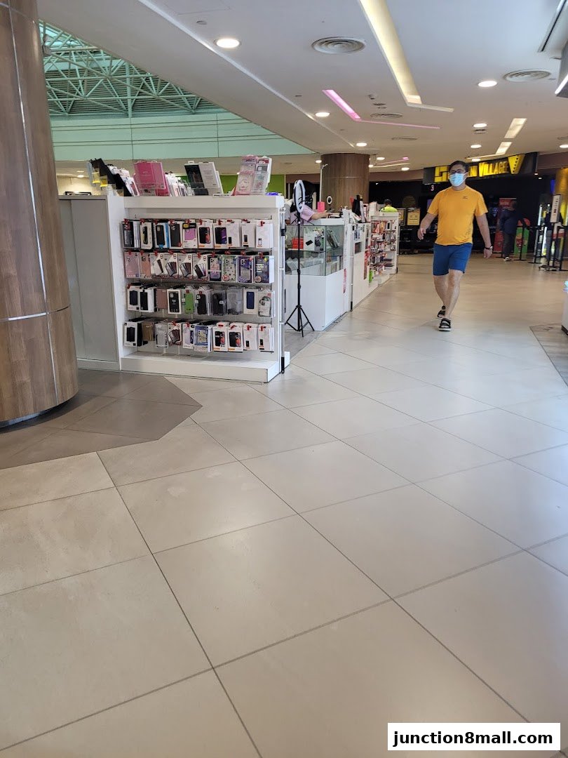 A retail shop displaying a wide variety of phone cases and accessories, with a customer walking by.