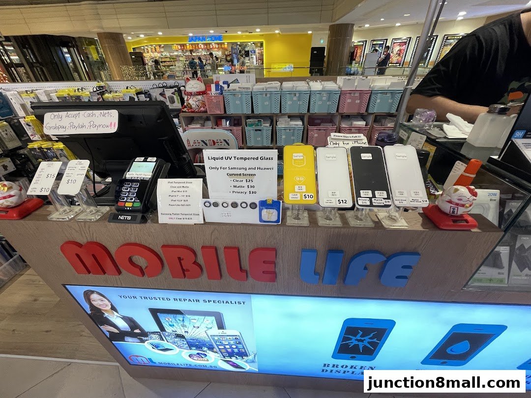 A mobile phone repair shop counter displaying tempered glass screen protectors and payment terminals.