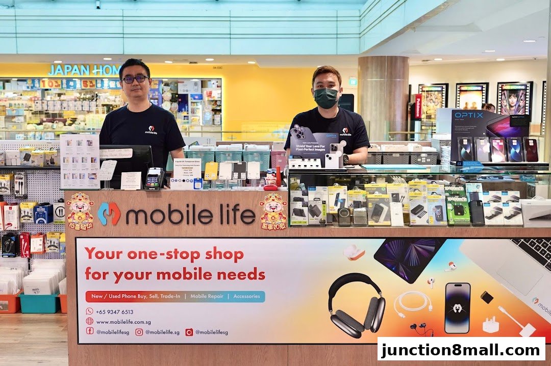 Two staff members stand behind a counter at Mobile Life, a shop selling phone accessories and offering repair services.