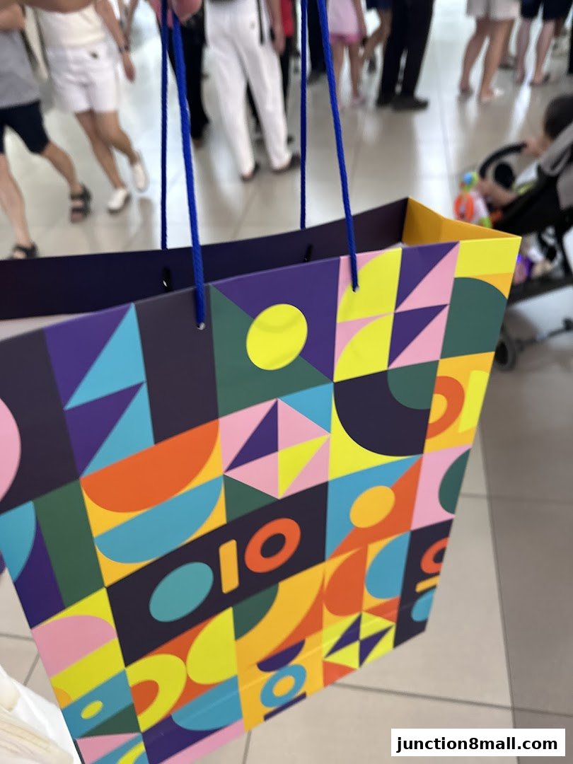 A colorful shopping bag with a geometric pattern held by blue strings.