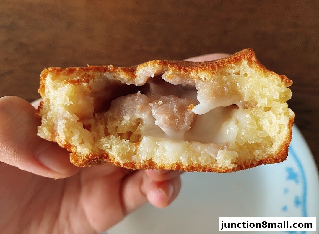 A close-up shot of a person holding a delicious-looking pastry filled with creamy custard and fruit pieces.