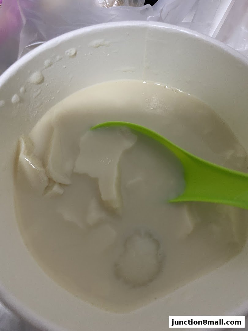 A close-up of a white bowl filled with a creamy dessert and a green spoon.