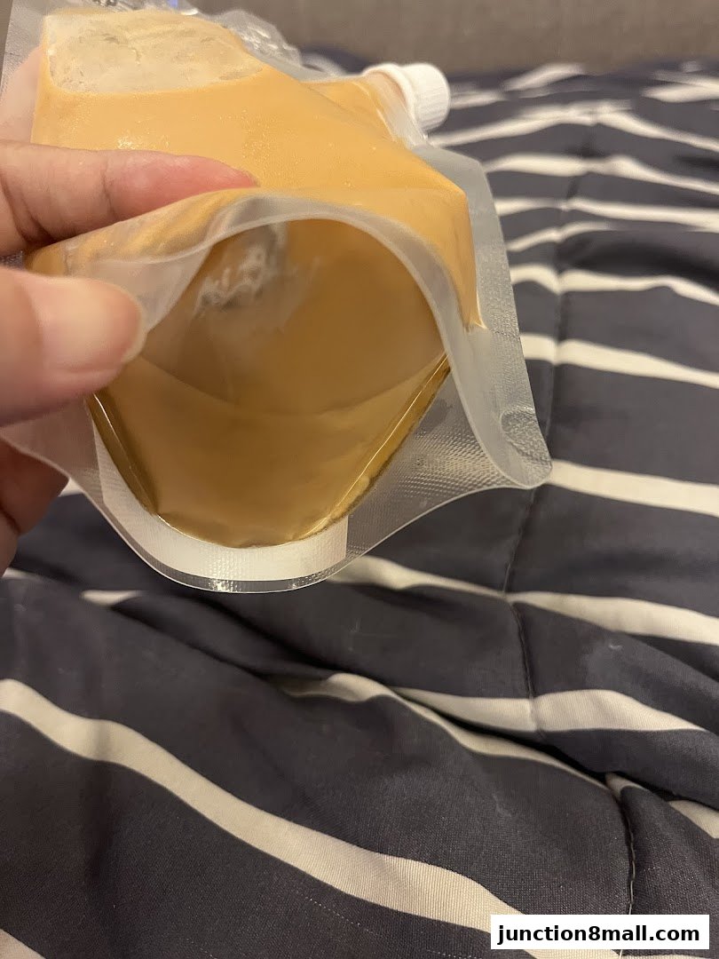 A hand holds open a pouch filled with a creamy, light brown substance.