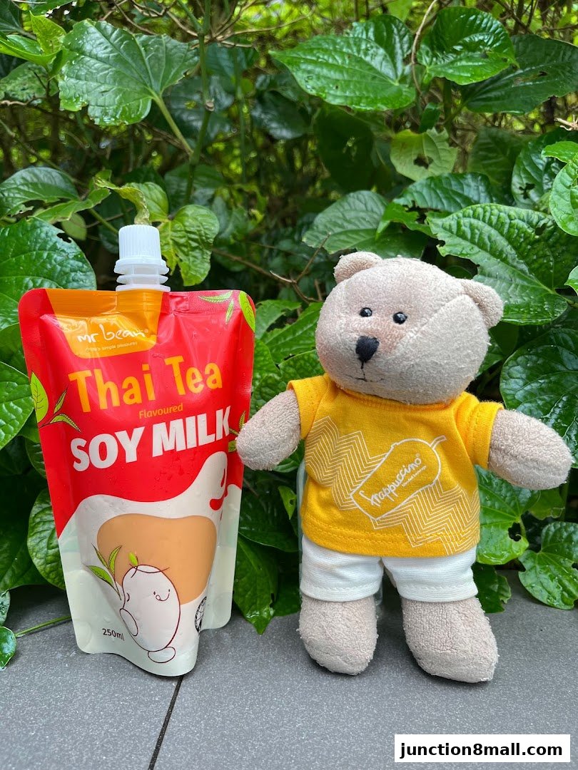 A teddy bear stands next to a pouch of Mr Bean Thai Tea flavored soy milk.