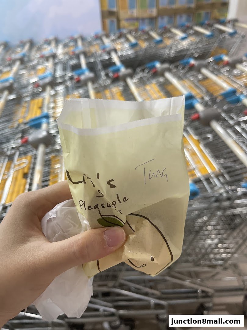 A hand holds a crumpled paper bag with handwritten text and a drawing.