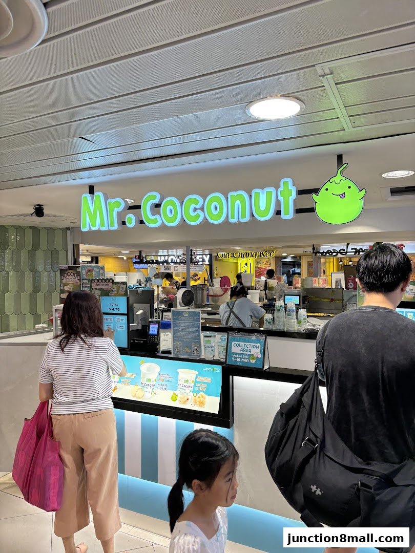 People queuing at the Mr. Coconut Junction 8 shop counter with bright signage.