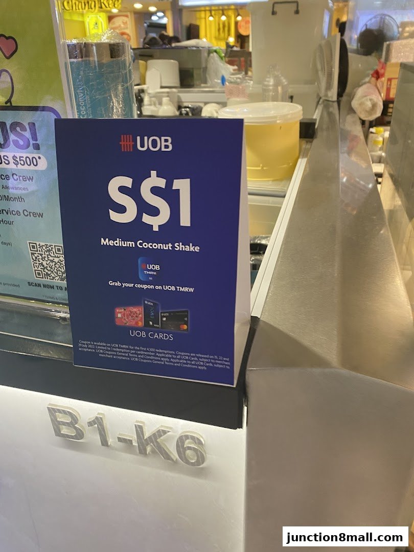 A sign advertising a $1 medium coconut shake from Mr. Coconut Junction 8 with UOB payment.