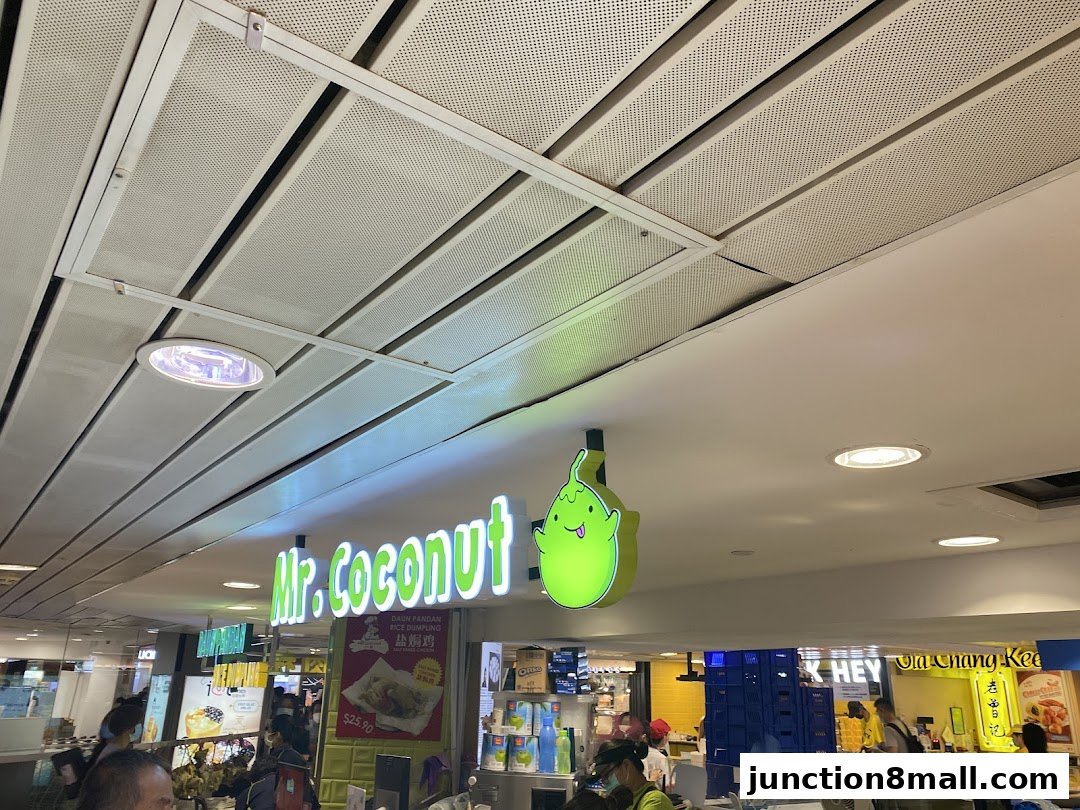 The illuminated sign for Mr. Coconut and other shops in a mall.