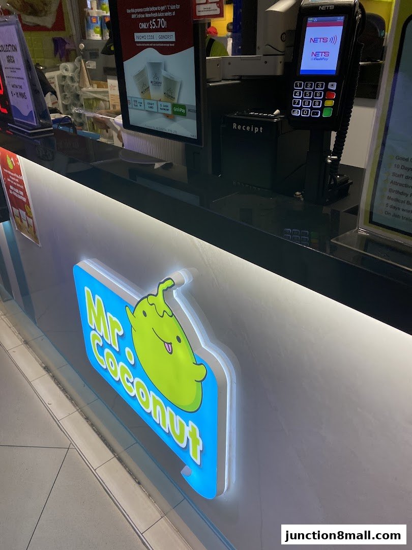 The illuminated sign for Mr. Coconut Junction 8, with a payment terminal and promotional display.