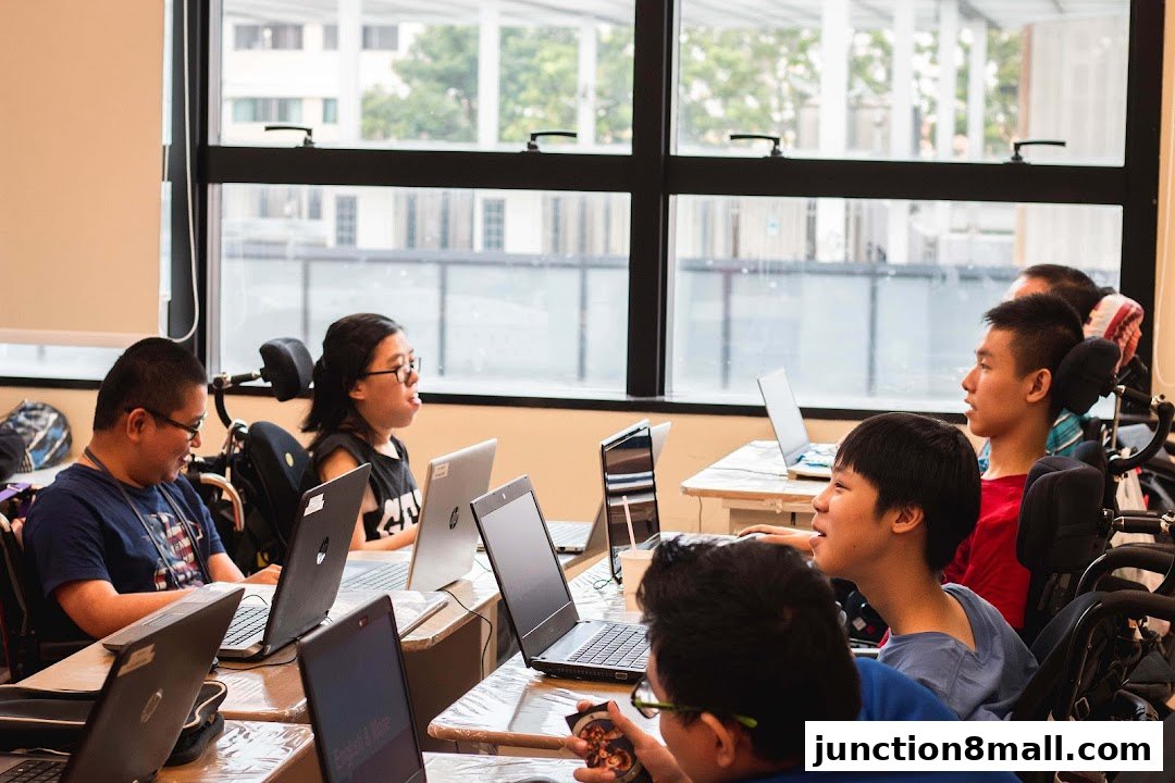 A group of young people in wheelchairs are engaged in a class with laptops.