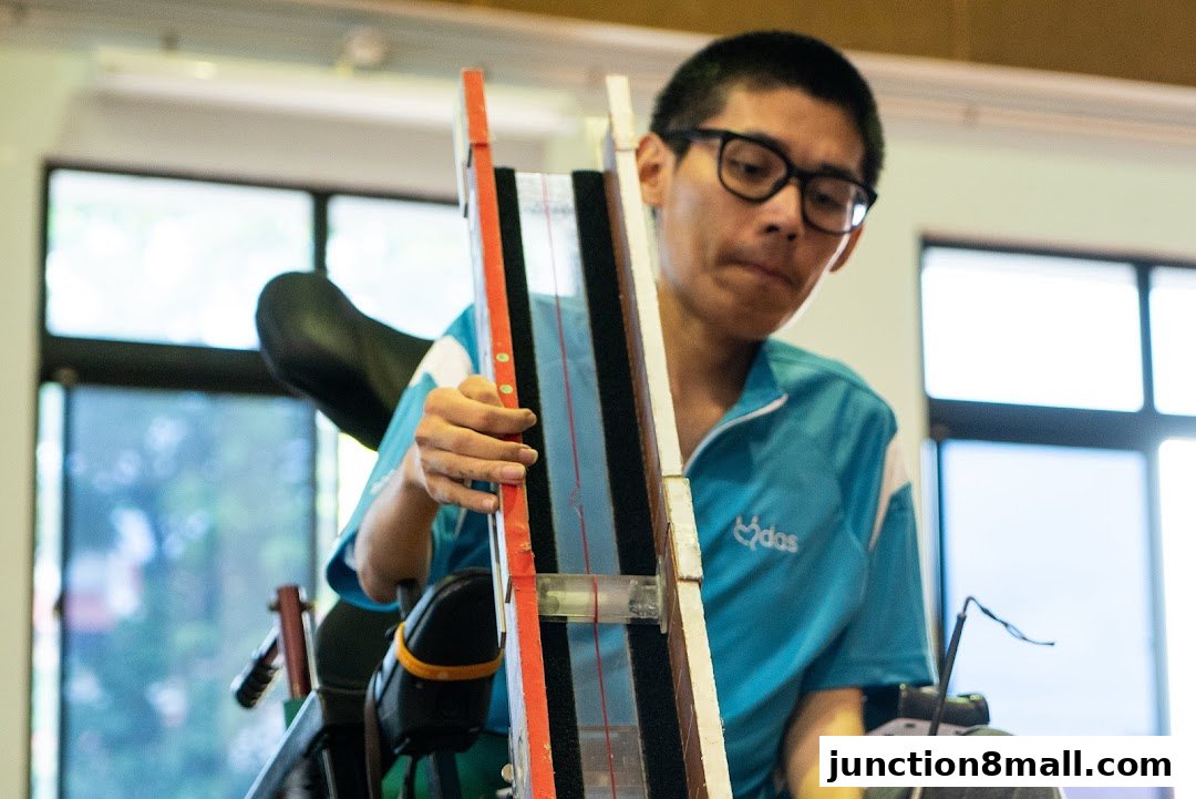 A young man in a wheelchair is holding a device with colorful stripes and a red edge.