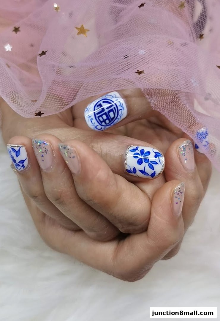 Close-up of hands with intricate blue and white nail art, featuring floral and Chinese character designs.