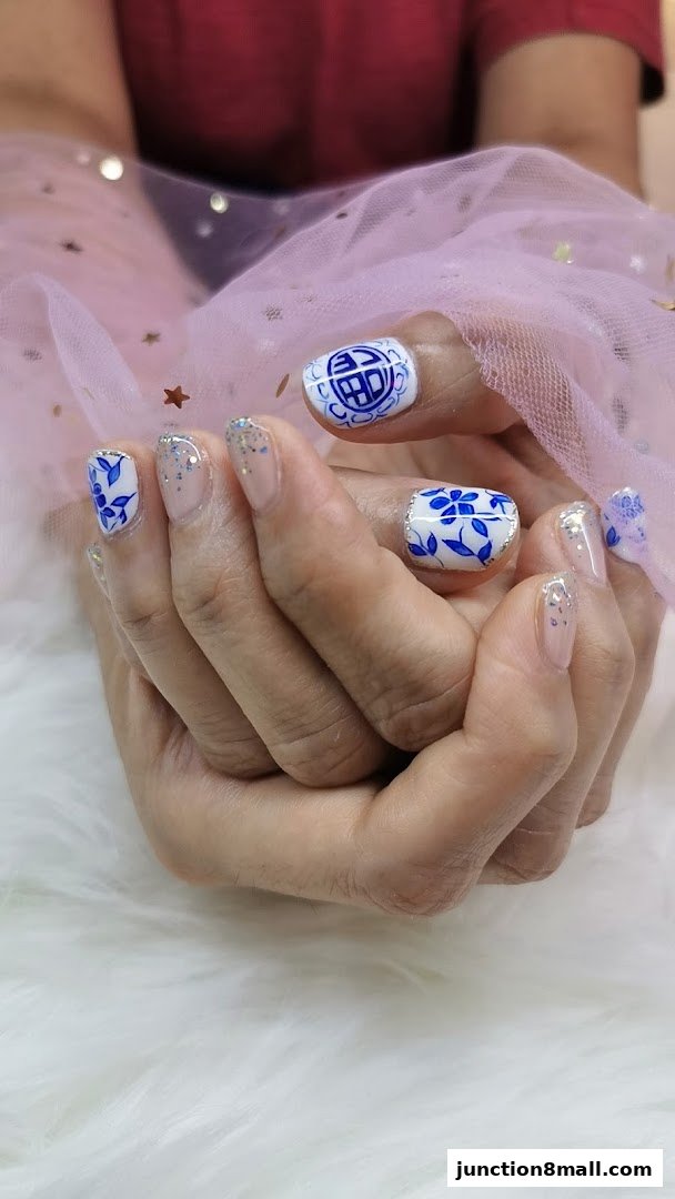 Close-up of hands with intricate blue and white nail art, adorned with glitter.