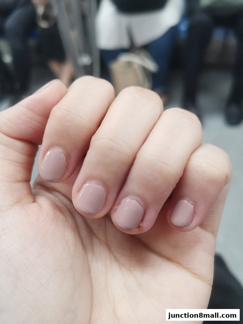 Close-up of a hand with neatly painted nude-colored fingernails.