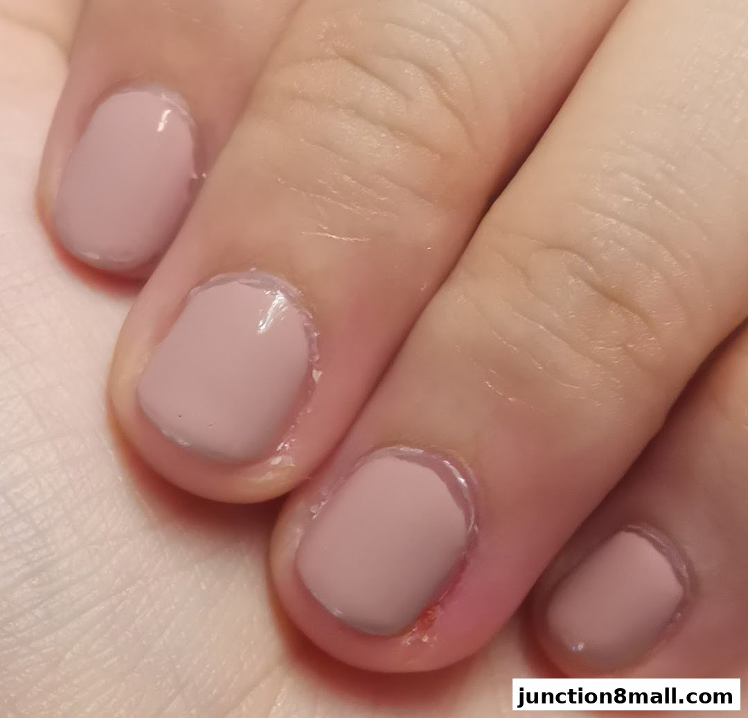 Close-up of a hand with neatly painted nude-colored fingernails.