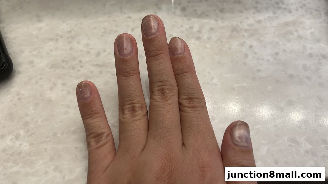 A close-up shot of a hand with light brown, glossy nail polish.