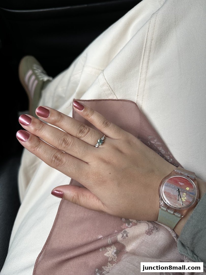 A close-up of a hand with metallic rose nail polish, a ring, and a watch.