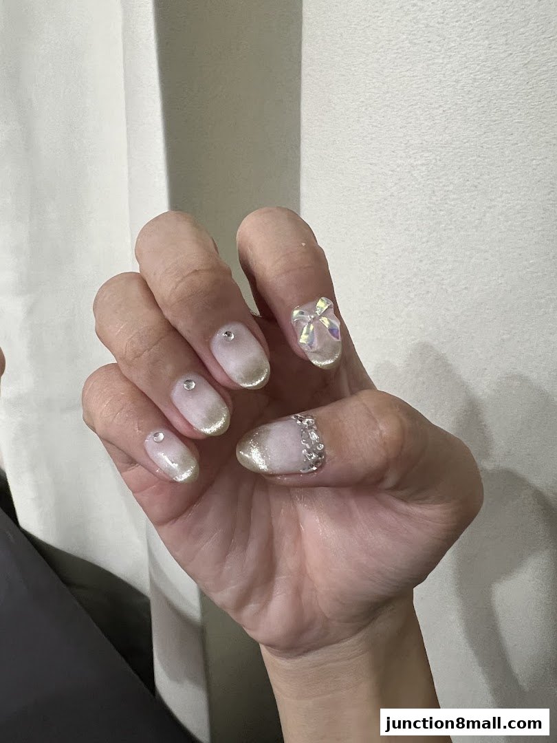 A close-up of a hand showcasing beautifully decorated nails with gems and glitter.