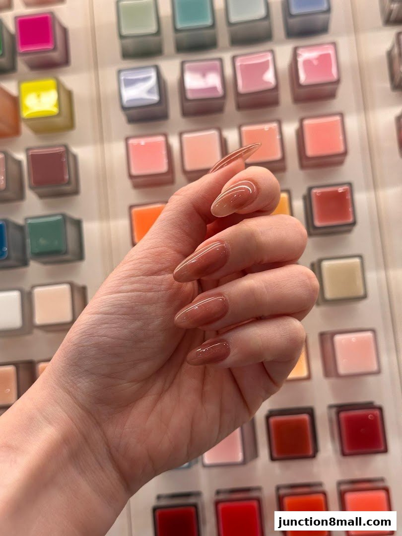 A hand with beautifully manicured nails showcasing a subtle ombre effect against a backdrop of colorful nail polish samples.