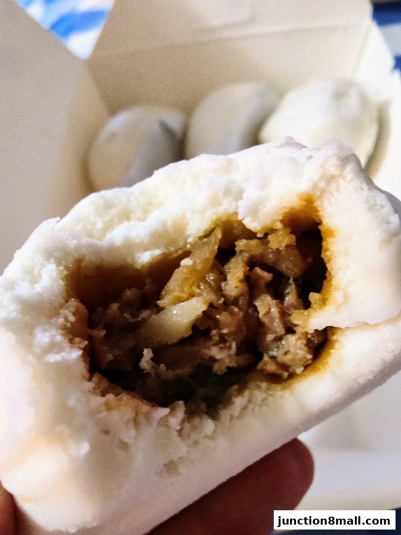 A close-up shot of a delicious steamed bun filled with savory meat.