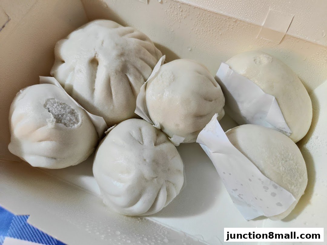 A box of steamed buns, some with visible fillings, ready to be enjoyed.