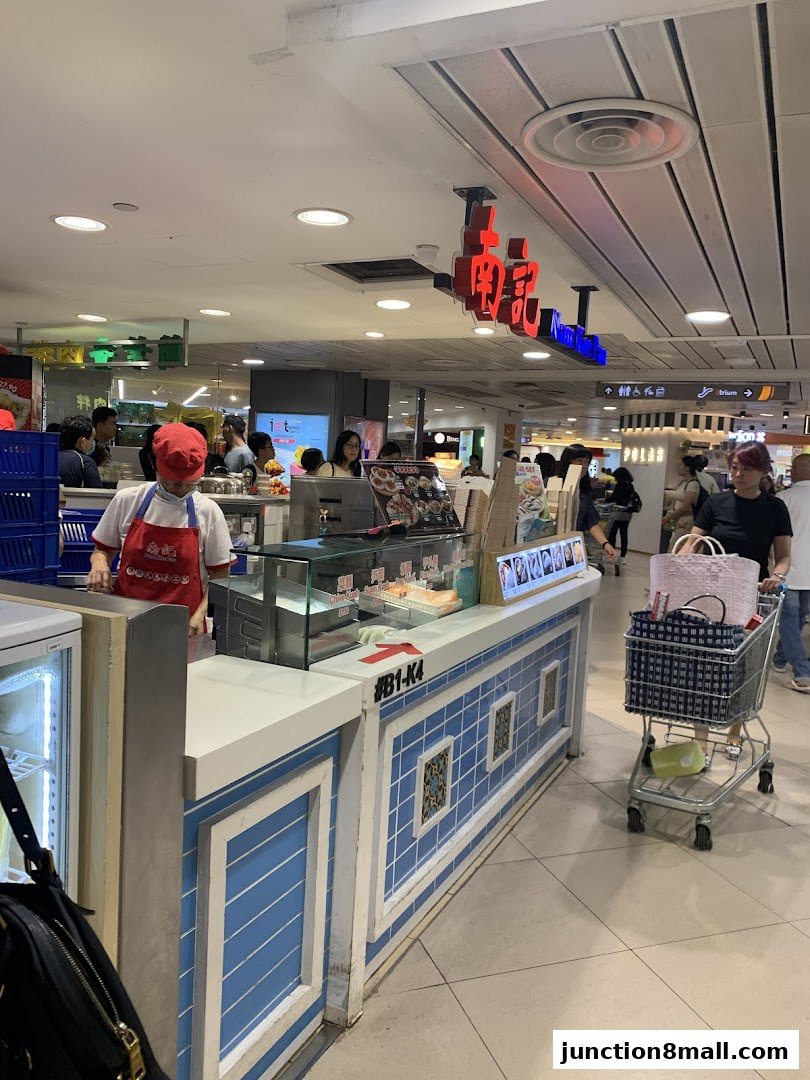 A food stall with a worker preparing food and customers browsing.
