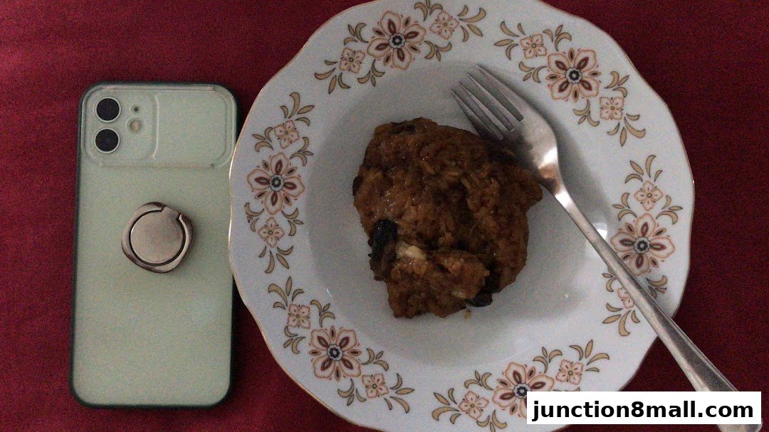 A close-up of a pastry on a decorative plate next to a smartphone.