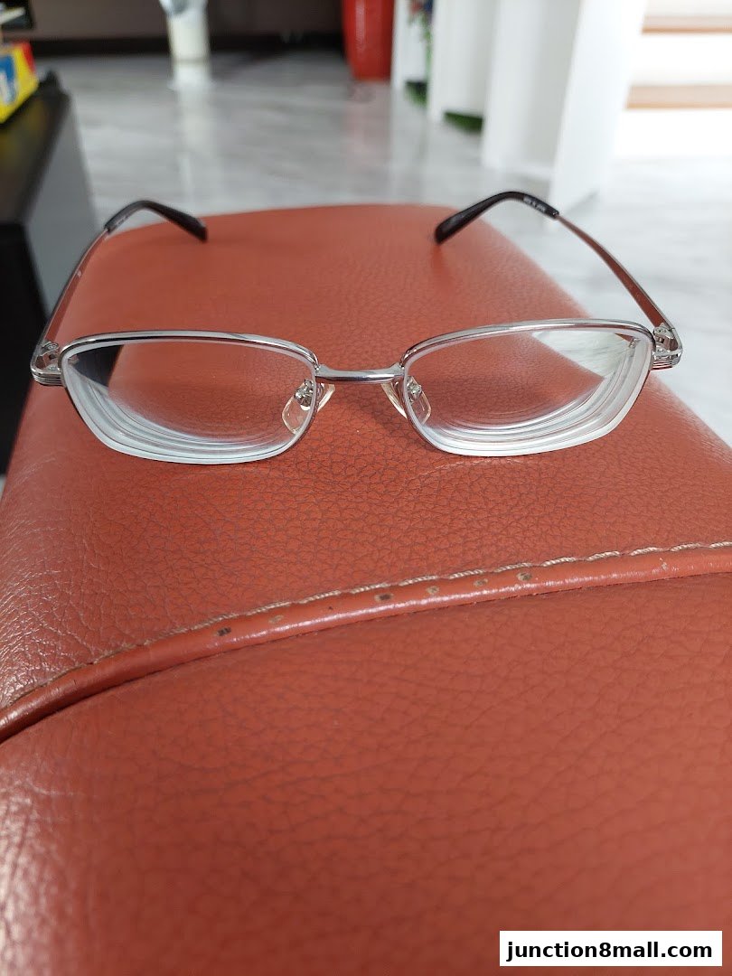 A pair of stylish, silver-rimmed eyeglasses with clear lenses rests on a brown surface.