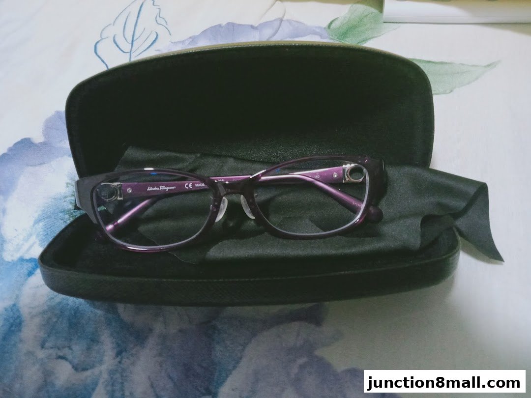 A pair of purple Salvatore Ferragamo eyeglasses in a black case.